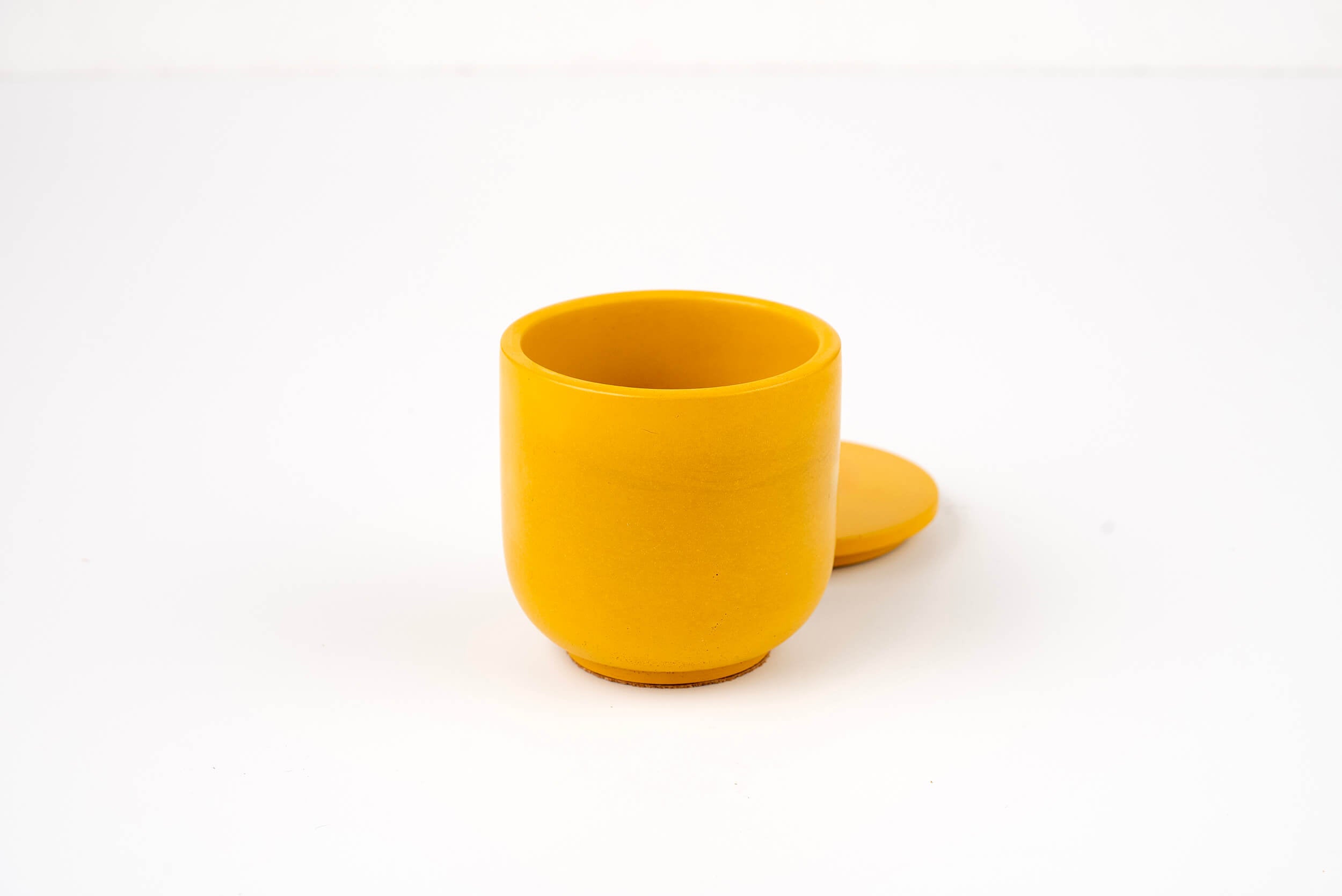 The Marigold Candle Vessel, in bright yellow with a matching lid set slightly behind, stands out against a plain white background.