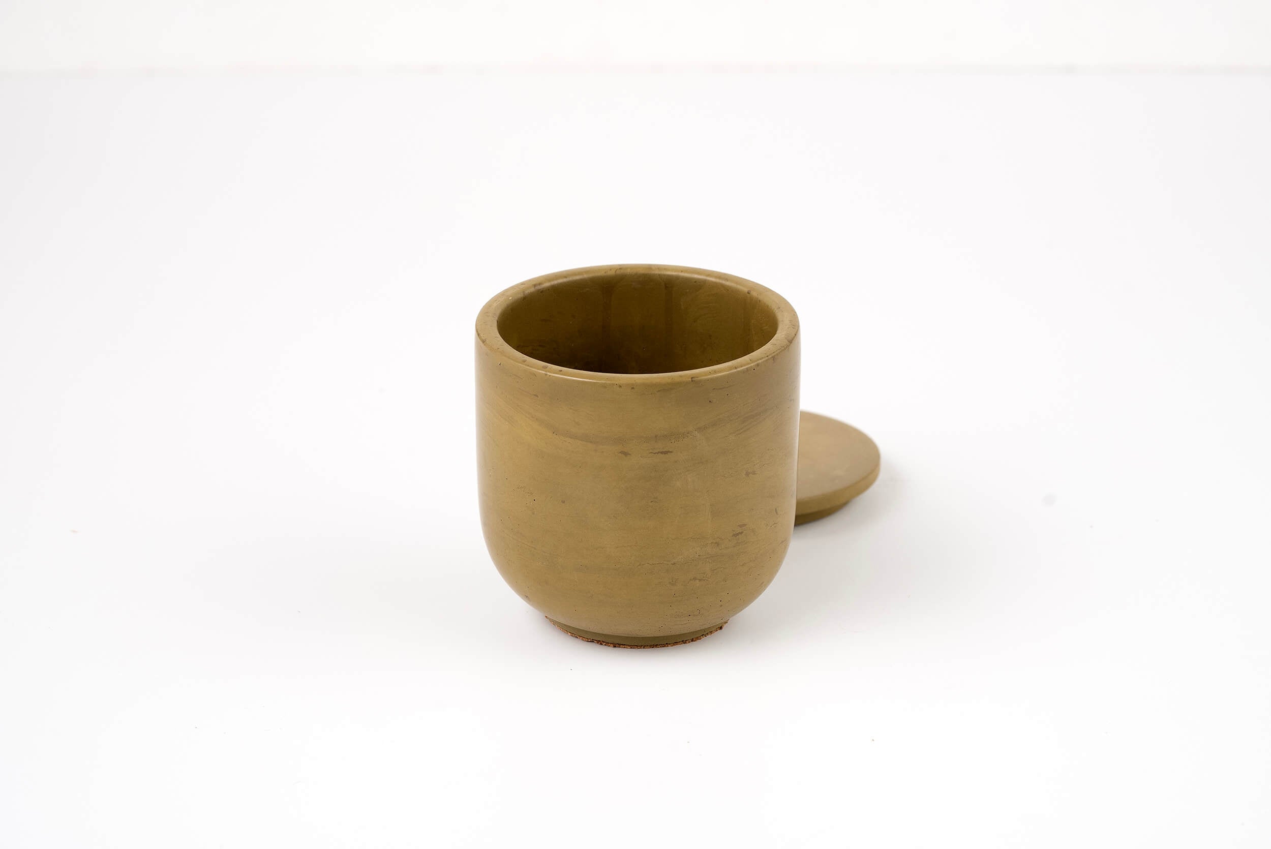 The Bark Candle Vessel is a small, round, brown clay vessel with a matching flat lid placed behind it on a white background—ideal for holding your favorite candle scent refill.