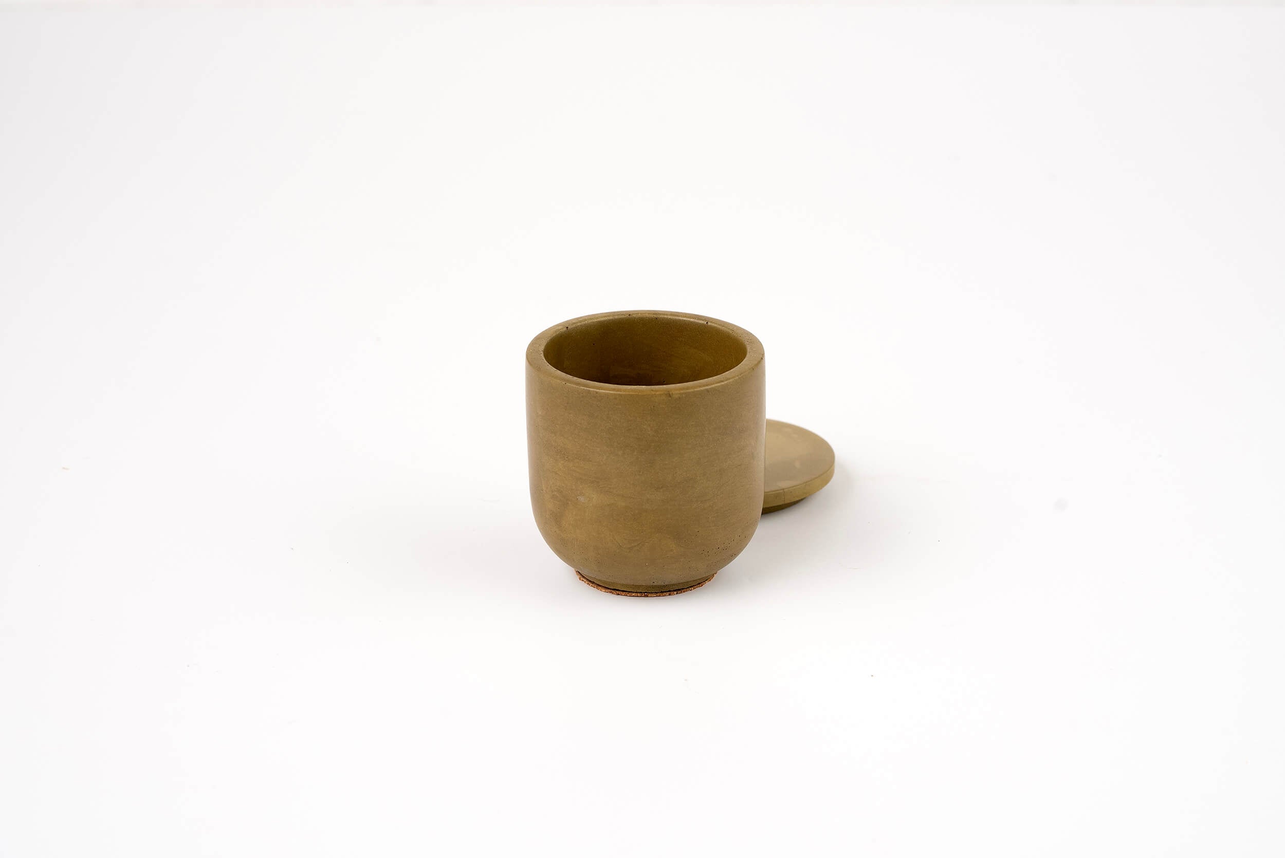 The Bark Candle Vessel is a small, light brown ceramic cup with a matching lid placed slightly behind it on a plain white background—ideal for elegantly holding your favorite candle scents.