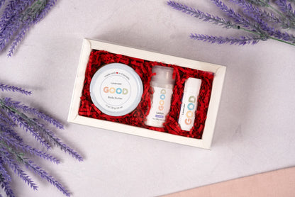 The Lavender Gift Set includes lavender body butter, lotion, and a GOOD-labeled Lavender Lip Balm, all arranged on a light surface with sprigs of lavender and red shredded paper filling the box.