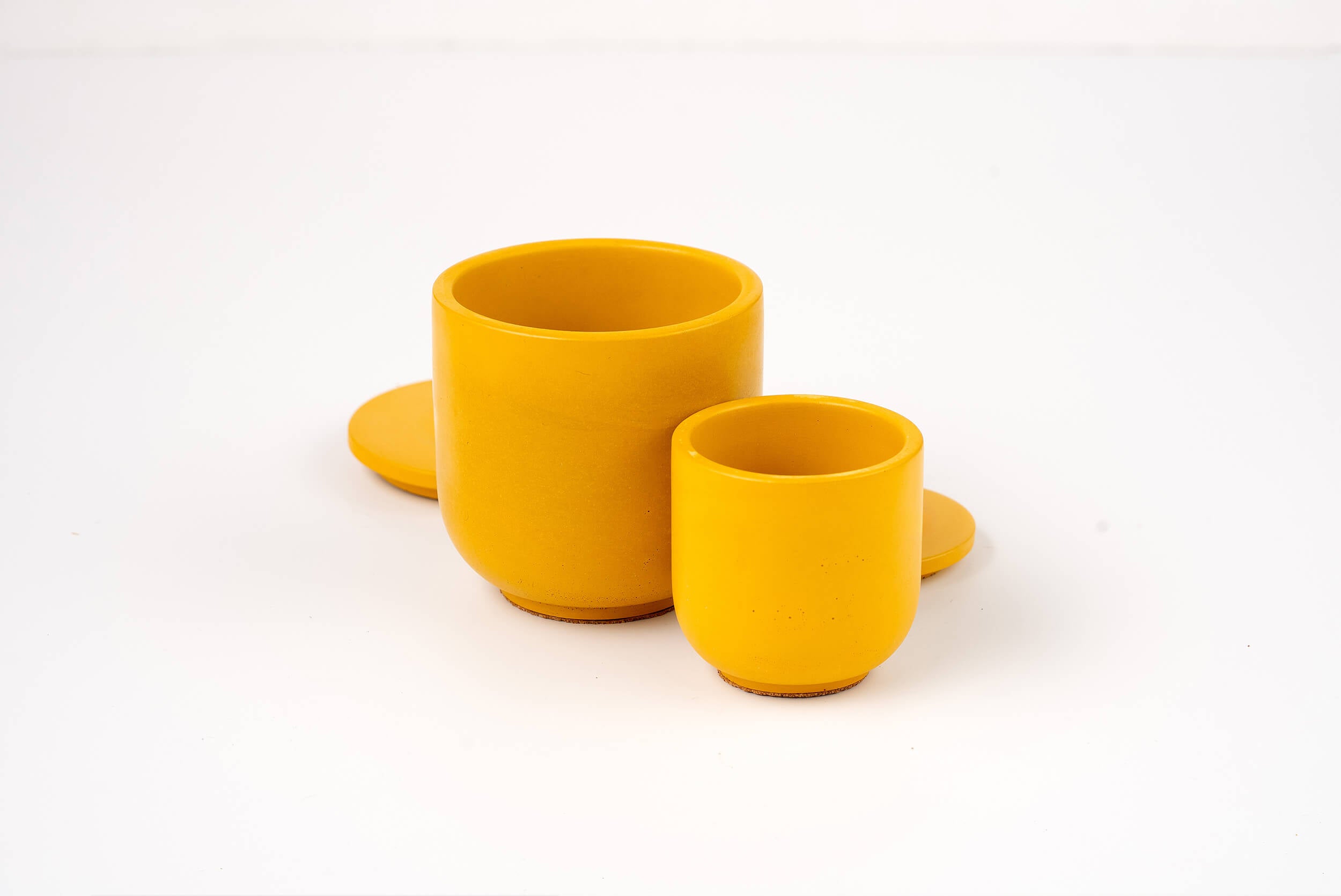 Two Marigold Candle Vessels in yellow, each a different size, with matching round saucers displayed on a plain white background.